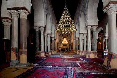 Photographie de la nef centrale de la salle de prière. Plus large et plus haute que les seize autres nefs, elle mène au mihrab. Elle est bordée, de part et d’autre, d’une double ligne d’arcades à colonnes géminées.