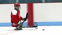 Un joueur de hockey sur luge maniant le palet.