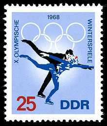 Un timbre avec un fond bleu et deux patineurs de patinage, la date 1968 est centrée sur le haut du timbre avec les anneaux olympiques. Le mot « Winterspiele » est écrit sur le côté droit, les mots « X Olympische » sont écrites sur le côté gauche. Le nombre 25 est dans le coin inférieur gauche et les lettres « DDR » sont dans le coin inférieur droit.