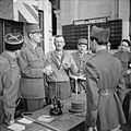 Des militaires gradés en uniforme français sont debout, autour de deux tables accolées, à l'intérieur d'un hall de la gare. En arrière plan, un tableau d'affichage des trains en partance.