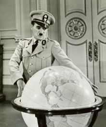 Capture d'écran montrant Chaplin en uniforme militaire avec une casquette à côté d'un large globe terrestre