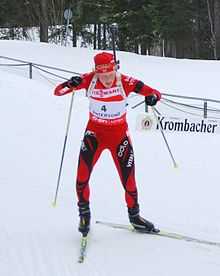 Biathlète debout de face, en train de pousser sur les bâtons.