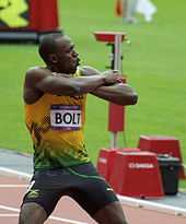 Photographie de Usain Bolt, bras croisés, à l'arrivée des séries du 200 m