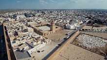 Photographie montrant une vue aérienne de la Grande Mosquée de Kairouan. Celle-ci est située à l’extrémité nord-est de la médina, à proximité des remparts dont elle n’est séparée que par une esplanade.