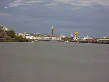 Vue de l'ouest du centre-ville de Nantes depuis la Loire : à droite une grue jaune, au centre un immeuble se détache, la tour Bretagne.