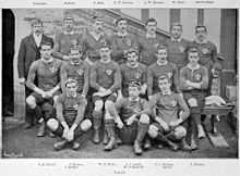 Photo de l'équipe du pays de Galles de rugby à XV prise avant la rencontre contre l'Angleterre lors du Tournoi britannique de 1895. Les quinze joueurs ainsi que l'entraîneur sont disposés sur trois rangées : trois joueurs sur celle du bas, six sur celle du milieu et les six derniers ainsi que l'entraineur sur celle du haut.