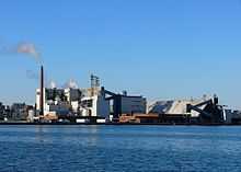 Une usine au bord de l'eau composé de plusieurs bâtiments.